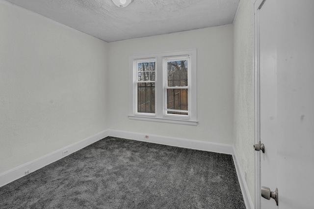 spare room with baseboards, dark carpet, and a textured ceiling