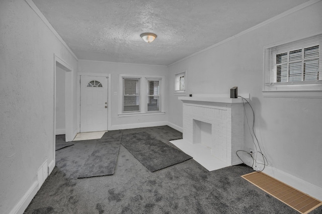 carpeted foyer entrance featuring a textured wall, ornamental molding, and a brick fireplace