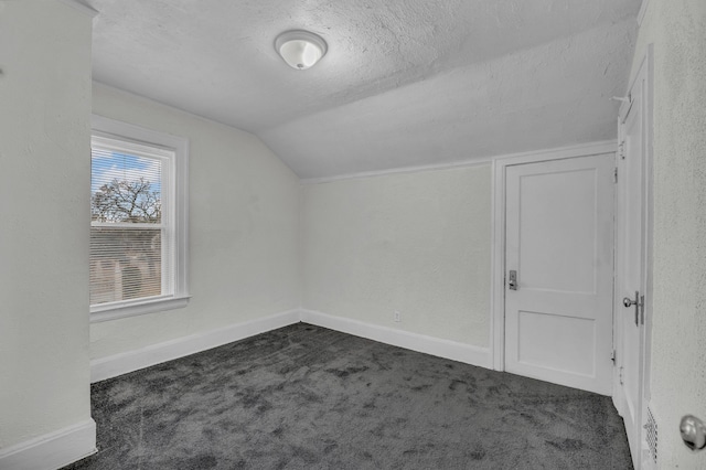 bonus room featuring vaulted ceiling, baseboards, dark colored carpet, and a textured ceiling