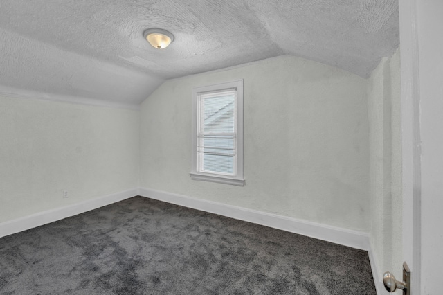 bonus room featuring a textured ceiling, dark colored carpet, lofted ceiling, and baseboards