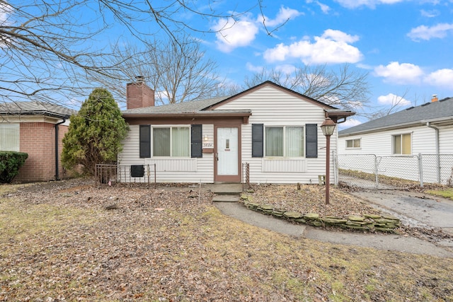 view of front of house featuring a shingled roof, a chimney, fence, and a gate