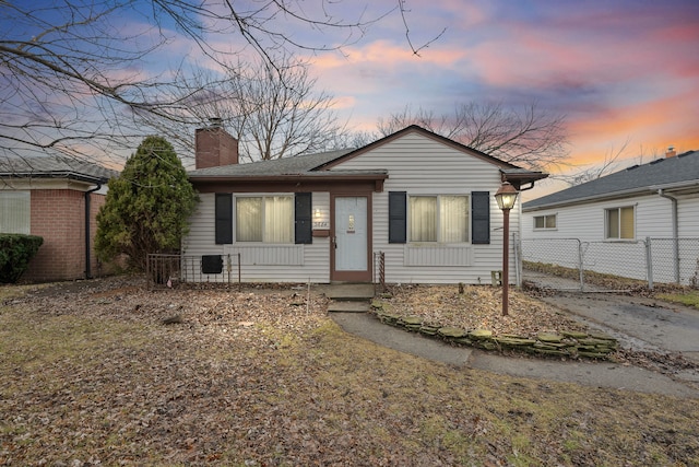 view of front of house with a shingled roof, a chimney, fence, and a gate