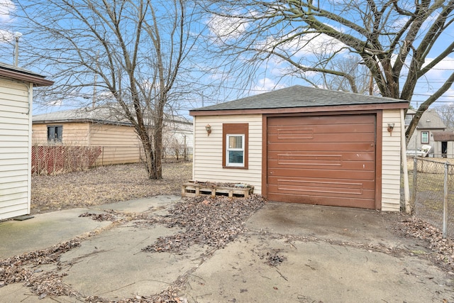 detached garage with concrete driveway and fence