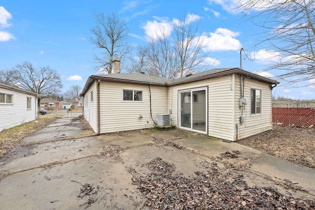 rear view of property with cooling unit, a patio, a chimney, and fence