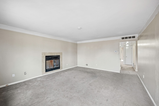 unfurnished living room featuring ornamental molding, carpet flooring, a tile fireplace, and visible vents