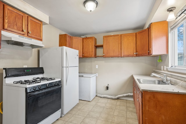 kitchen with gas range gas stove, light countertops, brown cabinetry, a sink, and under cabinet range hood