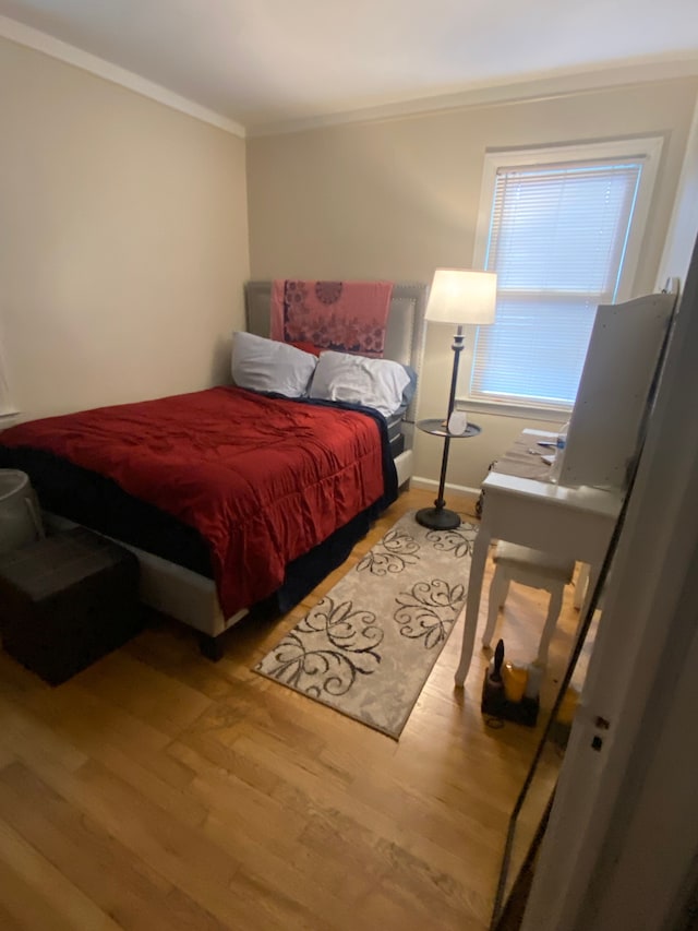 bedroom with baseboards, wood finished floors, and crown molding