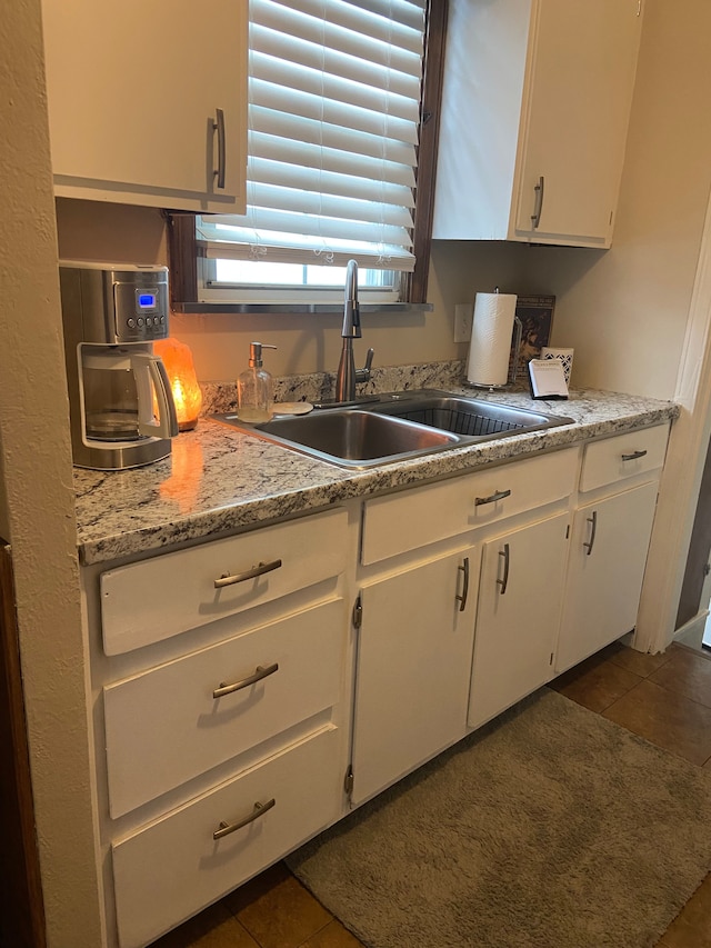 kitchen featuring light countertops, dark tile patterned floors, a sink, and white cabinetry