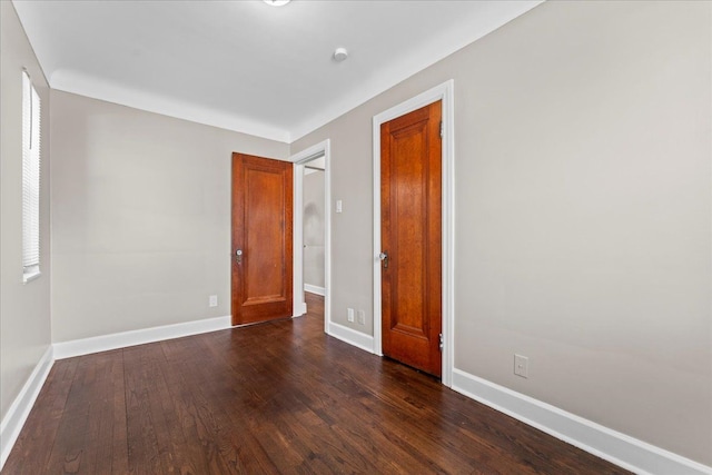 spare room featuring dark wood finished floors and baseboards