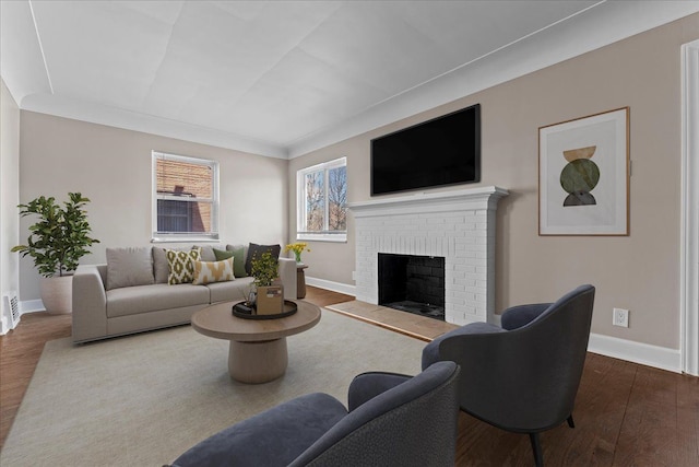 living room featuring a brick fireplace, dark wood-type flooring, and baseboards