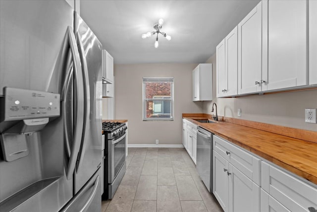 kitchen with butcher block counters, white cabinets, appliances with stainless steel finishes, and a sink