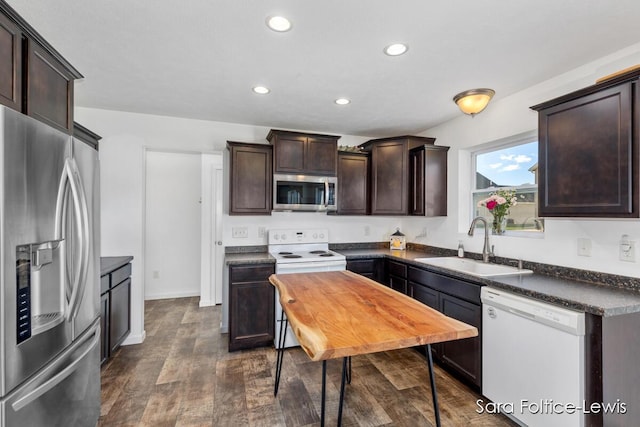 kitchen with dark brown cabinetry, stainless steel appliances, dark wood-style flooring, a sink, and dark countertops