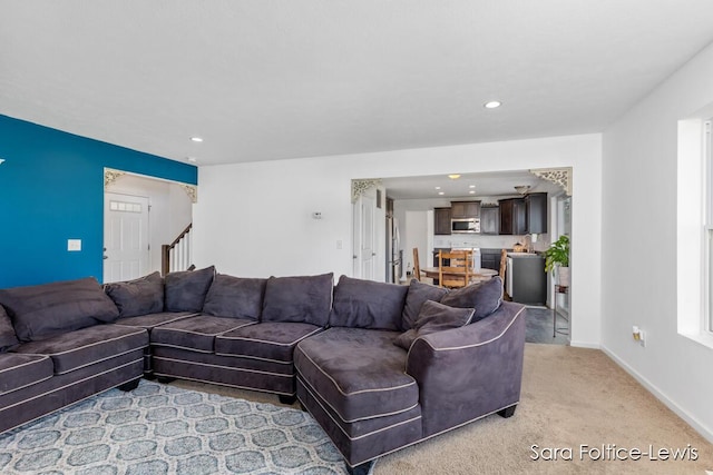 living room featuring recessed lighting, light colored carpet, stairway, and baseboards