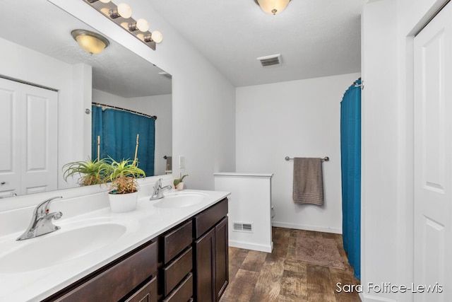 full bath featuring visible vents, a sink, and wood finished floors