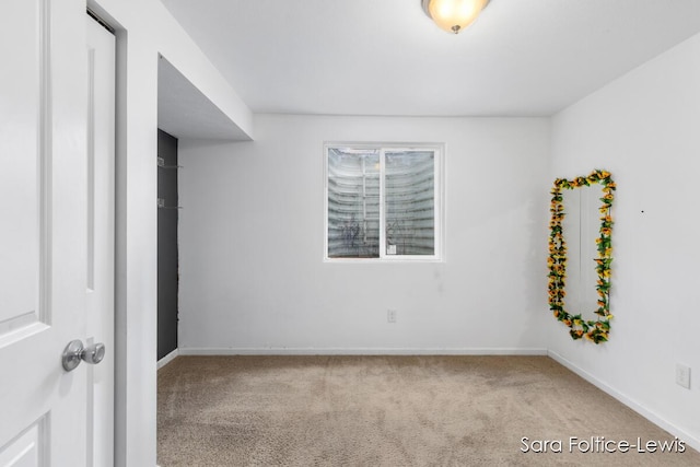 carpeted empty room featuring baseboards