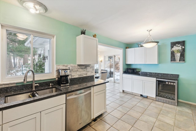 kitchen with wine cooler, a sink, white cabinets, stainless steel dishwasher, and dark stone countertops