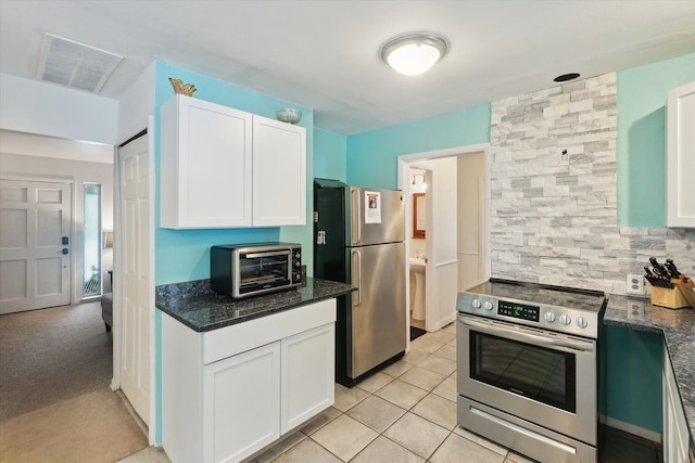 kitchen with light tile patterned floors, visible vents, white cabinets, dark stone counters, and stainless steel appliances