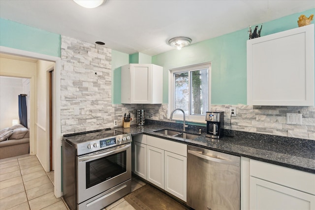 kitchen with a sink, white cabinetry, appliances with stainless steel finishes, dark stone counters, and tasteful backsplash