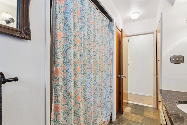 full bathroom with baseboards, stone finish floor, vanity, and a shower with curtain