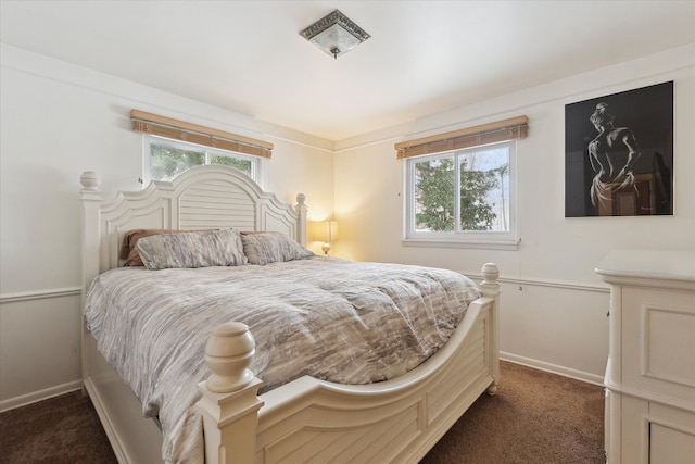 bedroom with dark carpet and baseboards