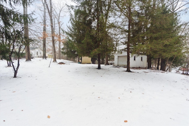 snowy yard with a garage and an outdoor structure