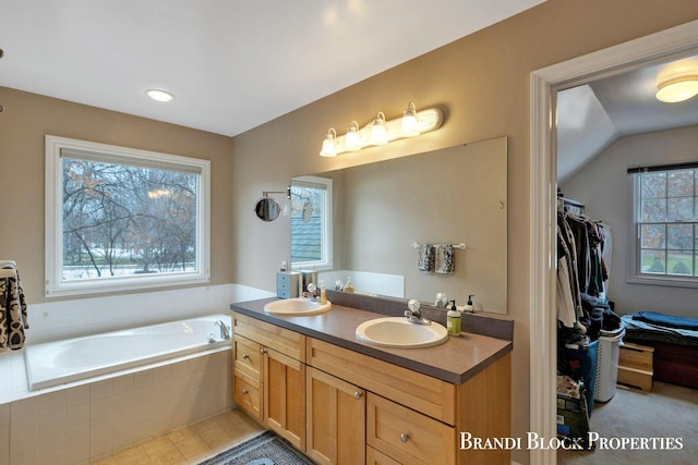 bathroom with a garden tub, a sink, and double vanity