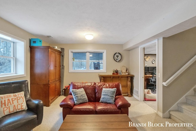 living area featuring light carpet, visible vents, stairway, and a textured ceiling