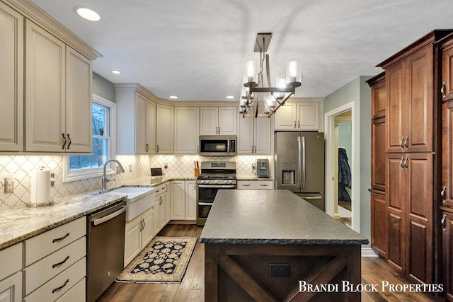 kitchen with stainless steel appliances, dark wood-type flooring, cream cabinets, and a sink