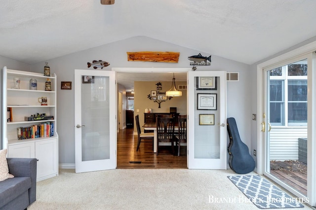 sitting room with visible vents, lofted ceiling, a textured ceiling, french doors, and carpet floors