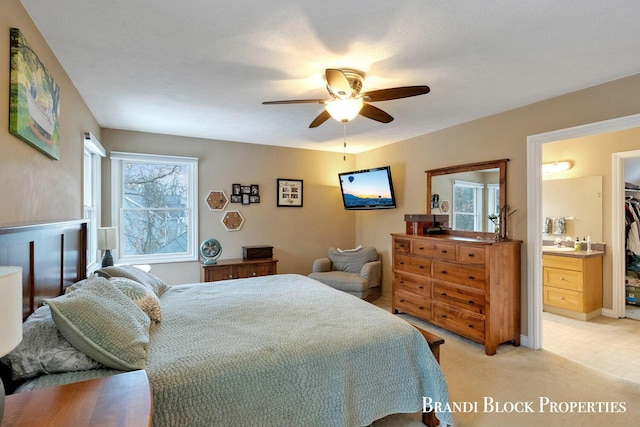 bedroom featuring a ceiling fan, light colored carpet, and connected bathroom