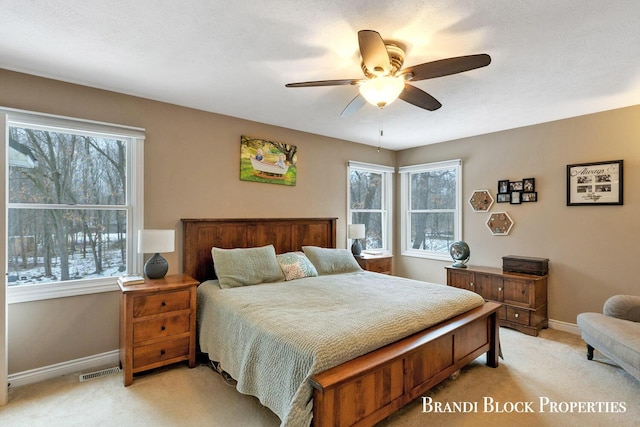 bedroom with light carpet, ceiling fan, visible vents, and baseboards