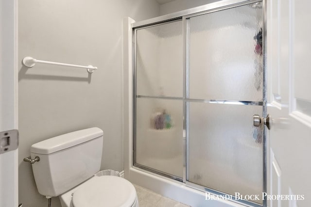 full bathroom featuring toilet and a shower with door