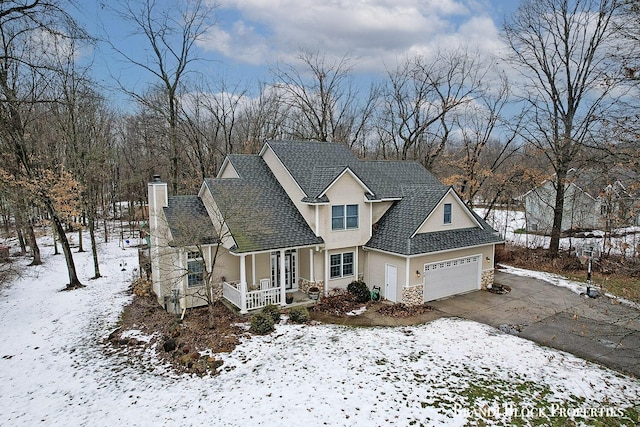 traditional-style house featuring driveway, stone siding, a chimney, an attached garage, and covered porch