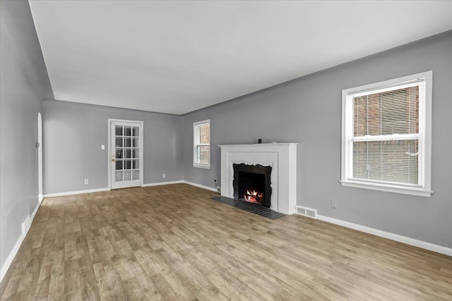 unfurnished living room featuring light wood finished floors, visible vents, and baseboards