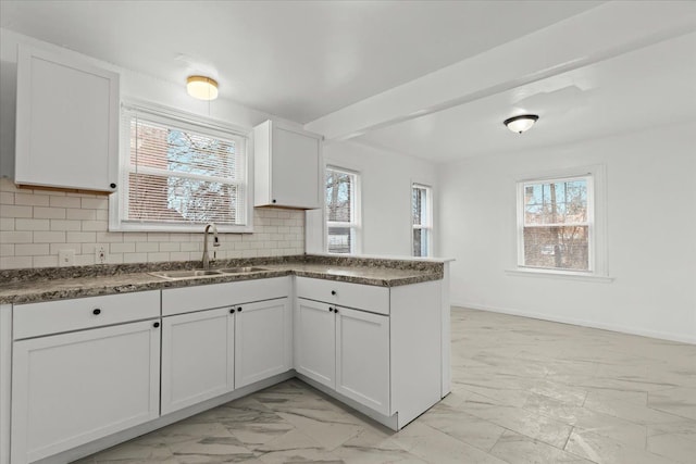 kitchen featuring tasteful backsplash, marble finish floor, a sink, and a peninsula