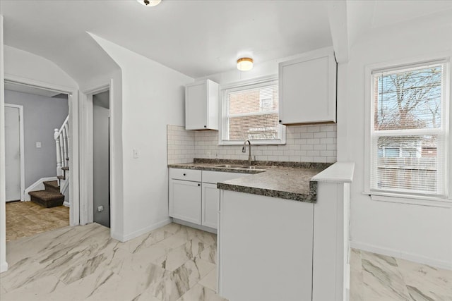 kitchen with dark countertops, marble finish floor, decorative backsplash, and a sink