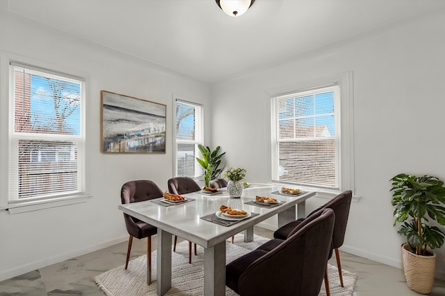 dining space featuring marble finish floor and baseboards