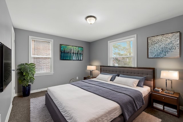 bedroom featuring multiple windows, dark carpet, and baseboards