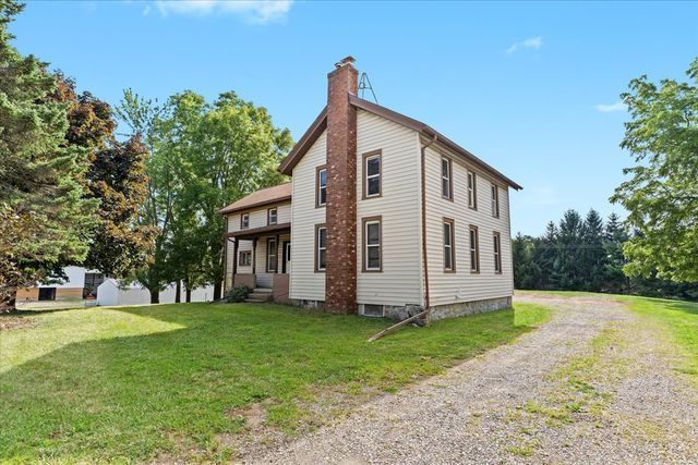 exterior space featuring driveway, a chimney, and a front yard