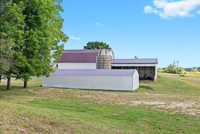 rear view of property featuring an outbuilding, a lawn, and an outdoor structure