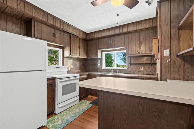 kitchen with light countertops, light wood-style flooring, decorative backsplash, a sink, and white appliances