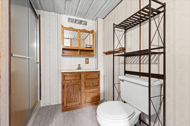 bathroom featuring toilet, a shower stall, wood finished floors, and vanity