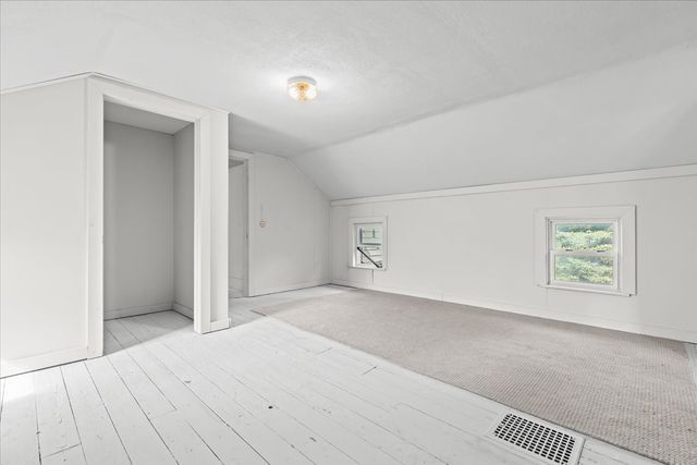 bonus room with lofted ceiling, visible vents, baseboards, and wood finished floors