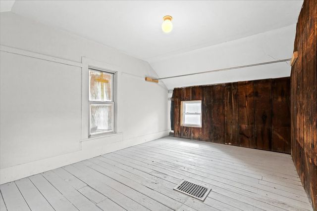 interior space with lofted ceiling, wood walls, visible vents, and hardwood / wood-style flooring