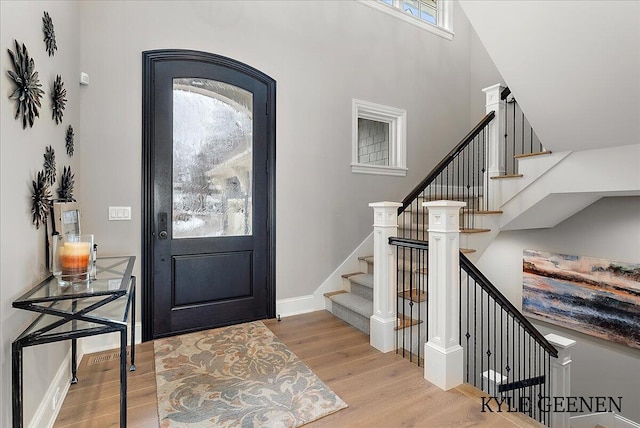 entryway featuring stairs, a high ceiling, wood finished floors, and baseboards