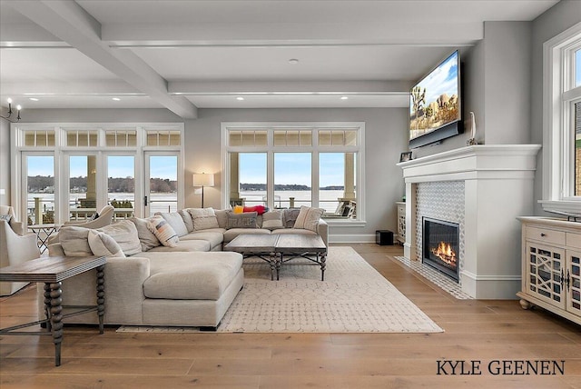 living area featuring baseboards, a tiled fireplace, hardwood / wood-style floors, beam ceiling, and recessed lighting