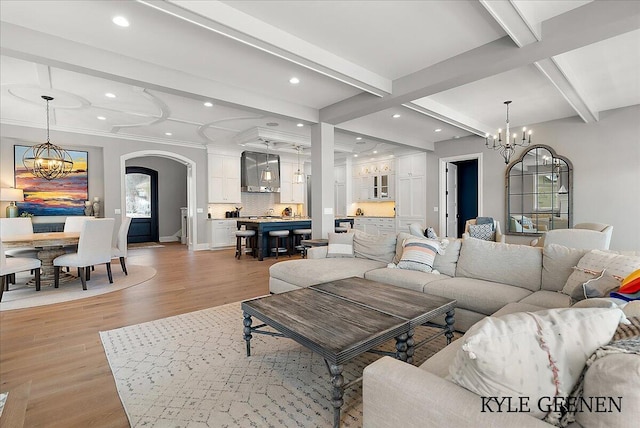 living area featuring arched walkways, a chandelier, and beam ceiling