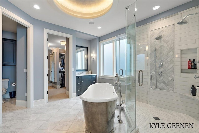 bathroom with toilet, vanity, baseboards, a freestanding bath, and a shower stall