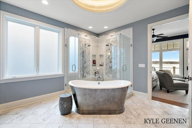 ensuite bathroom featuring ensuite bathroom, a stall shower, a soaking tub, and baseboards
