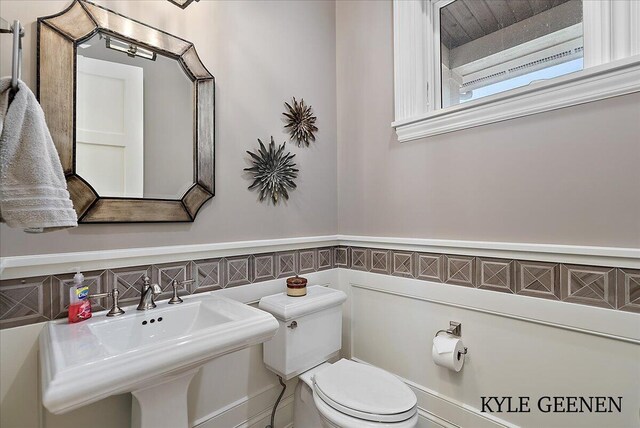 bathroom featuring a wainscoted wall, a sink, and toilet